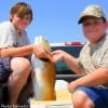 Fishin Buds Barry Spradling and Ethan Purvis of Bryan TX hold up a REAL BRUTE of a tagger Bull Red caught from the surf